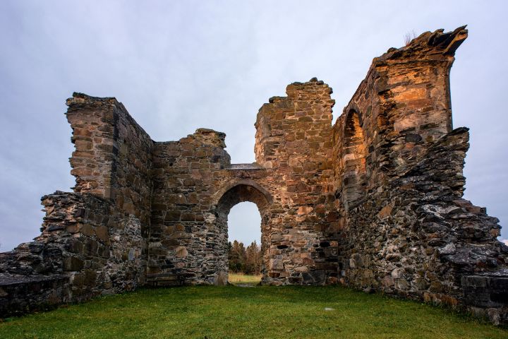 a large stone building with grass in front of a rock