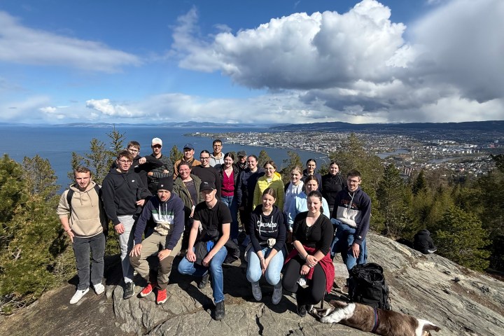 Group of people posing on a rocky hill with a city and sea in the background.