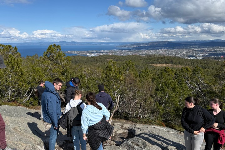 Group of people hiking on a rocky hill with a distant city view.