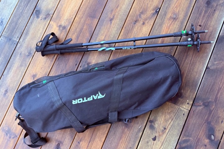 Two trekking poles and a black Raptor bag on a wooden floor.