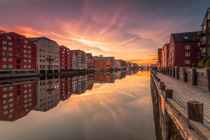 Sunset over a canal with colorful buildings reflecting in calm water.