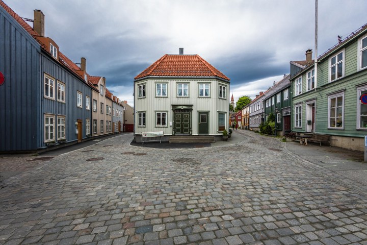 Cobblestone street with colorful houses and overcast sky.